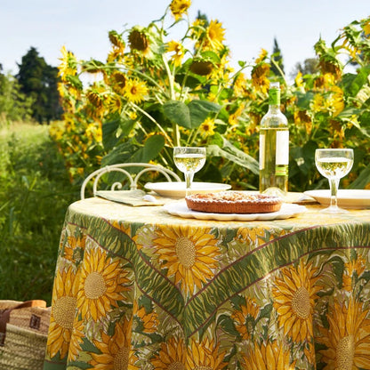 Table set with a sunflower-patterned tablecloth, pie, and wine glasses in a sunflower field.
