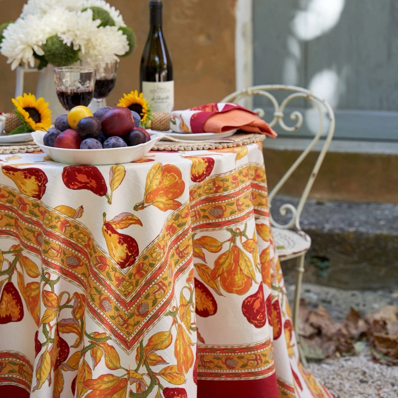 Decorative tablecloth with autumnal design on a table set outdoors.