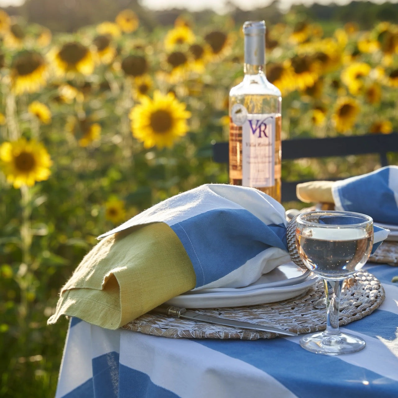 Table setting with a bottle of VR wine and a glass in a sunflower field