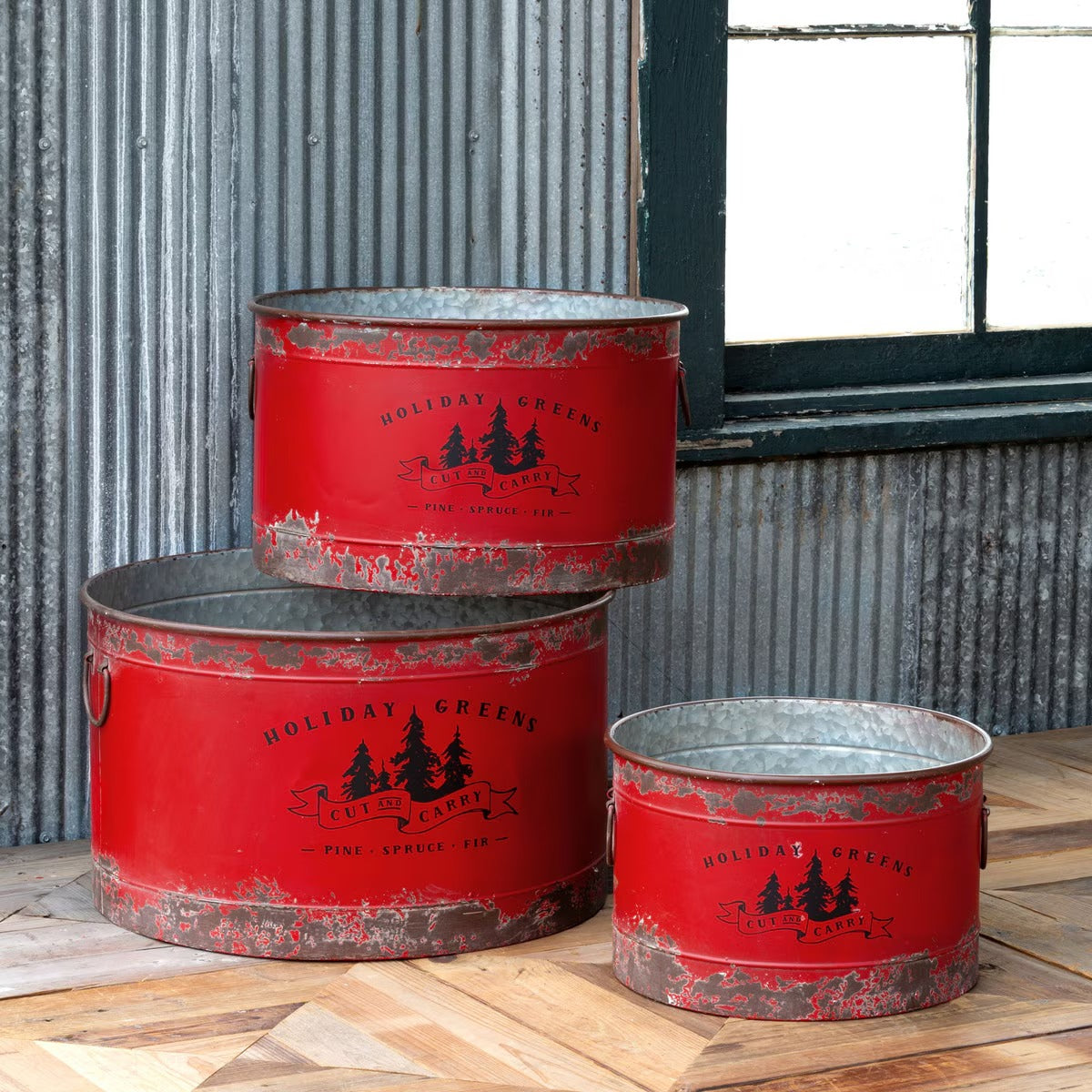 Set of three red metal buckets with 'Holiday Green' branding on a wooden surface.
