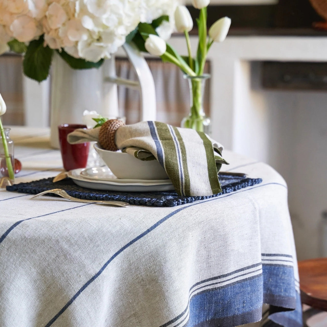 Table setting with a white tablecloth, napkin, and floral arrangement.