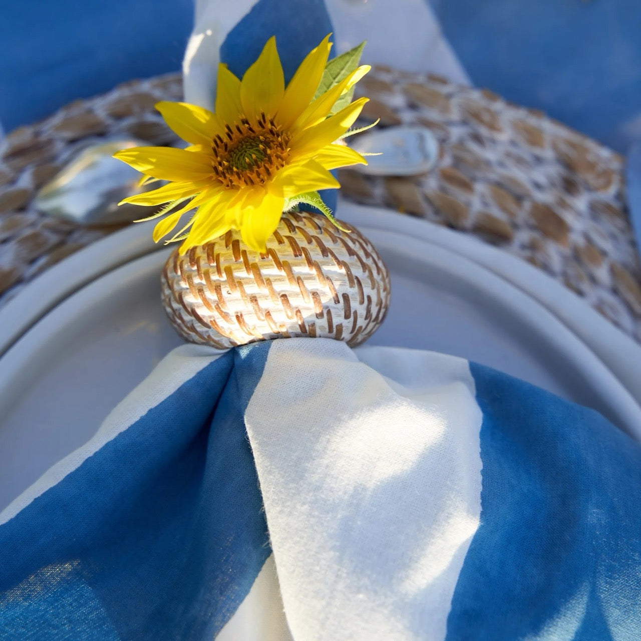 Yellow sunflower in a woven holder on a blue and white napkin