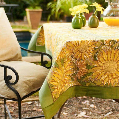 Outdoor setting with a tablecloth featuring sunflower design, chair, and potted plants.