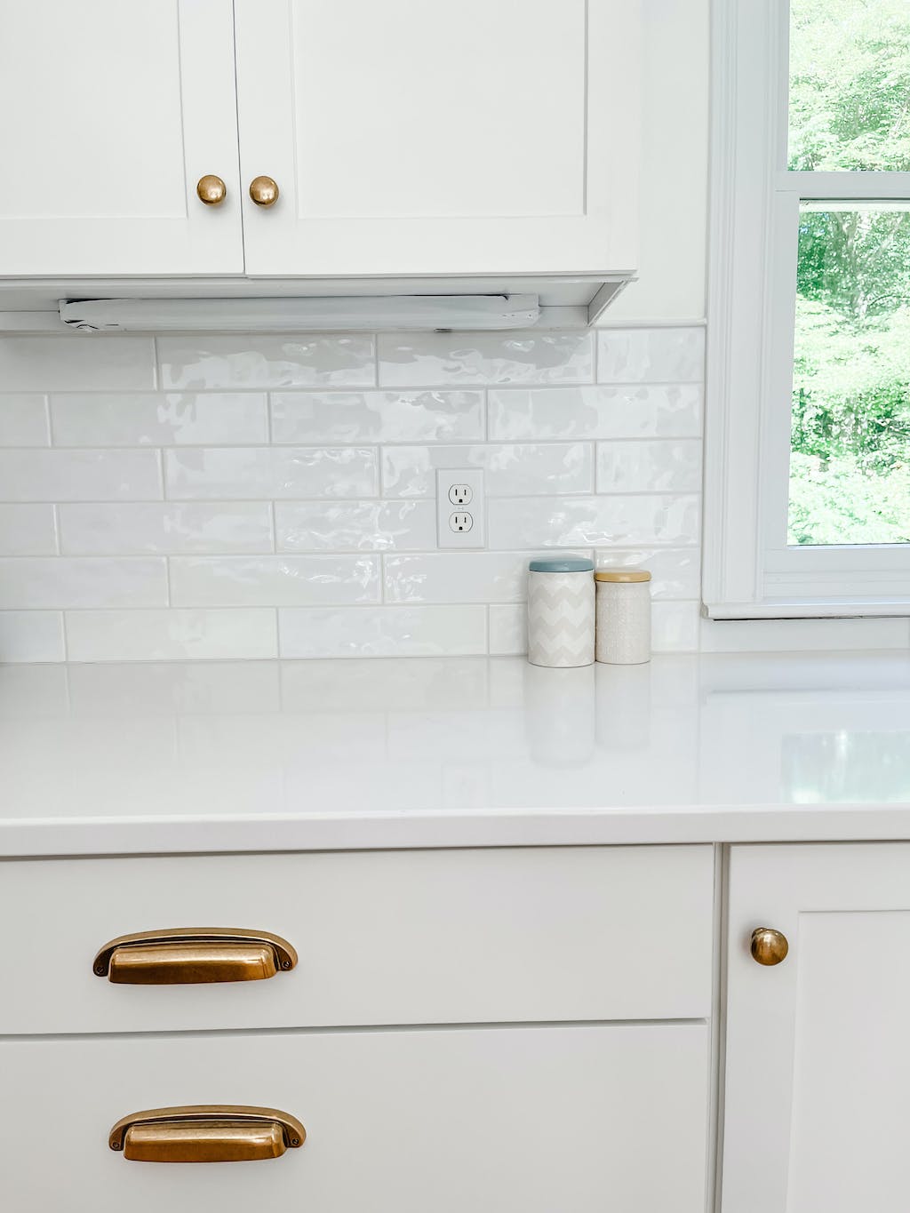 Kitchen with white cabinets, gold handles, and a tiled backsplash.