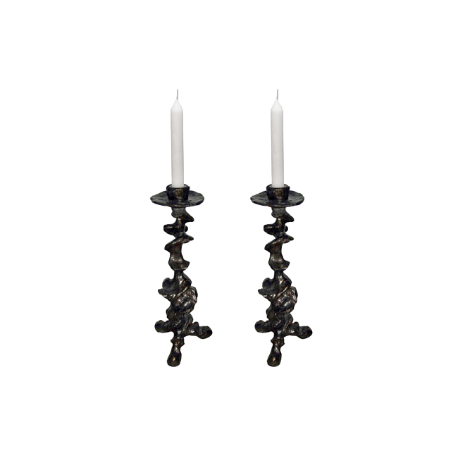 Two ornate black candle holders with white candles on a white background