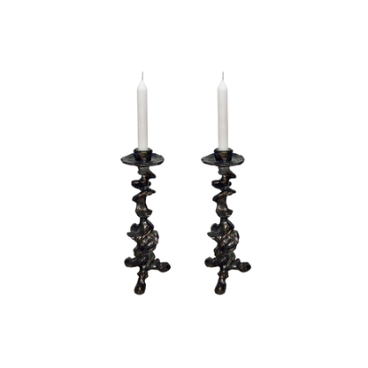 Two ornate black candle holders with white candles on a white background