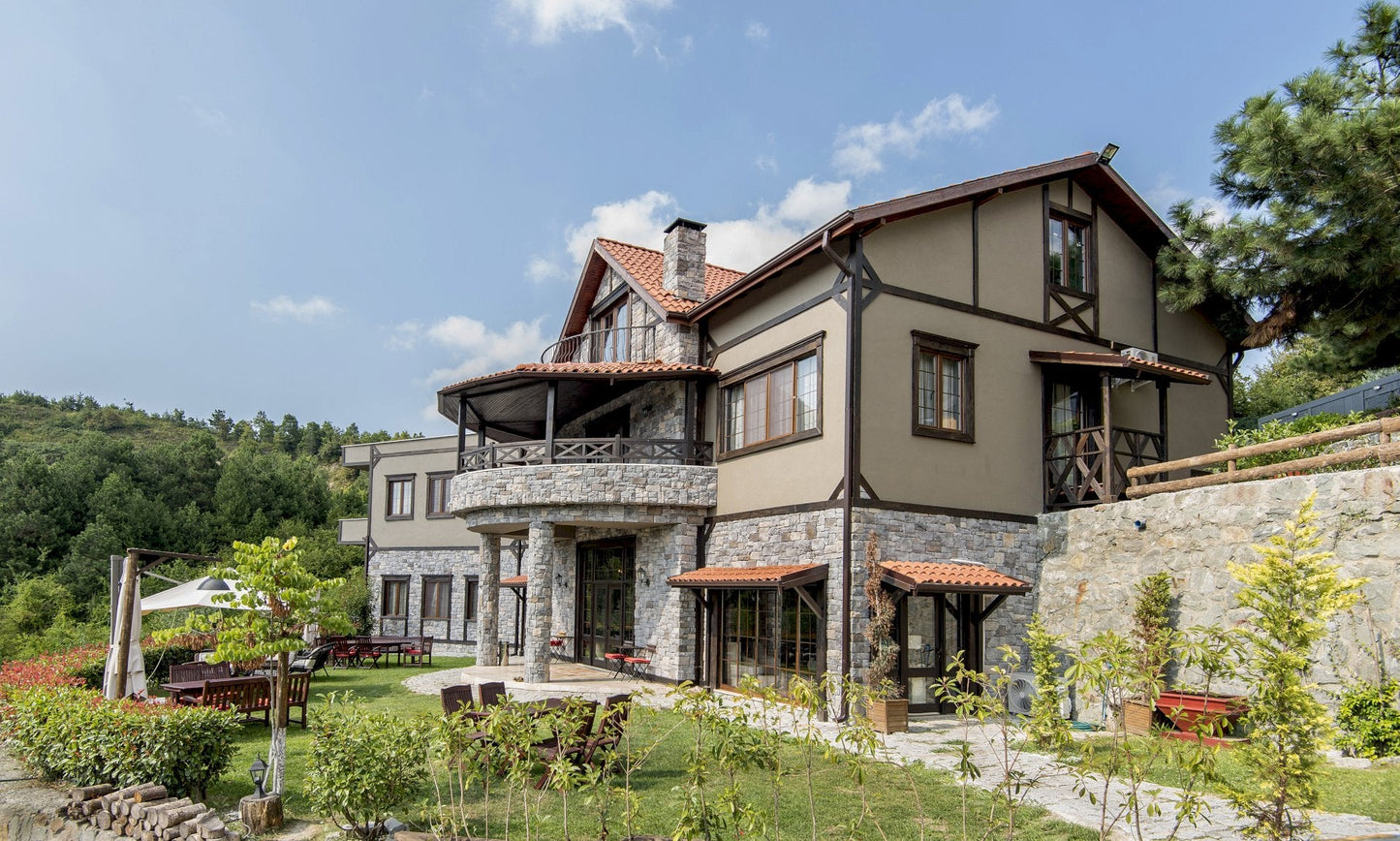 Large stone house with a garden and trees in the background