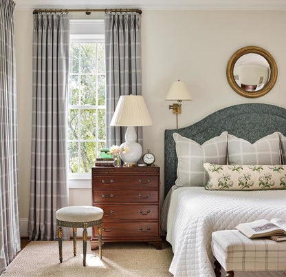 Neatly decorated bedroom with a bed, nightstand, and window with plaid curtains.