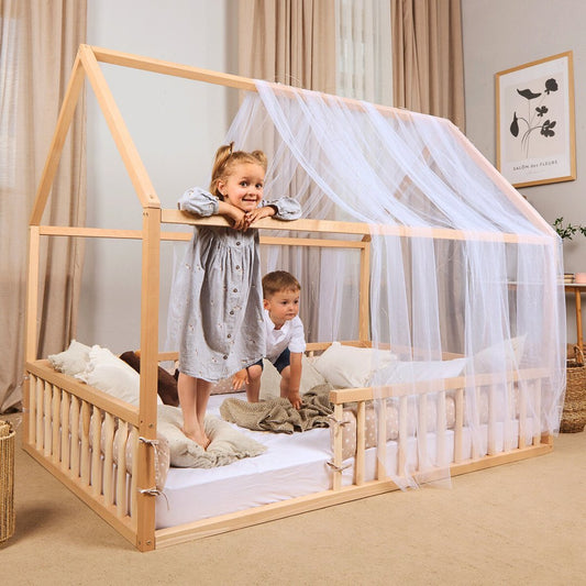 Children playing on a Montessori designed wooden bed with canopy in a room.