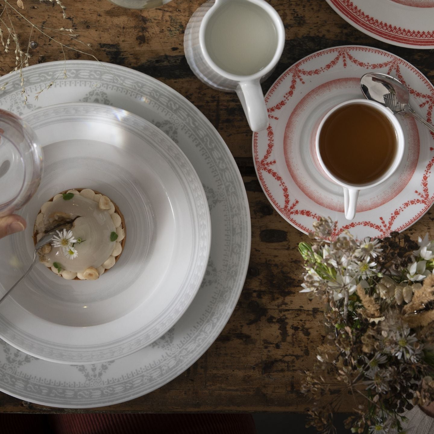 Tea time setting with a teacup, saucer, and dessert on a wooden table.